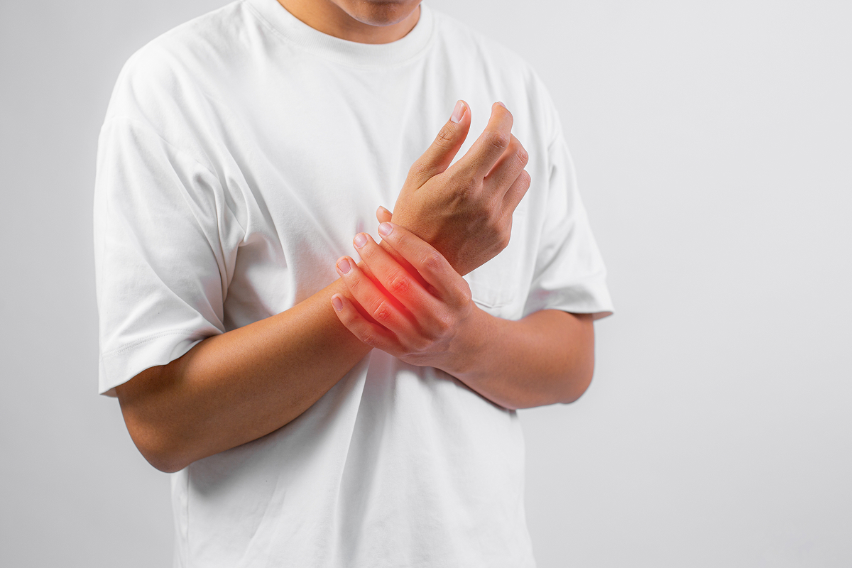 Person holding their wrist with visible redness indicating pain or inflammation.