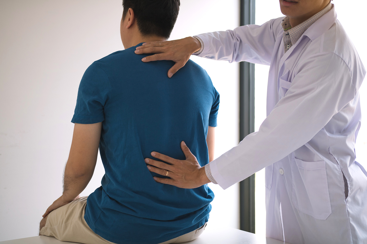 A therapist adjusts a sitting man's back. London Chiropractic is committed to helping you feel your best all year round.