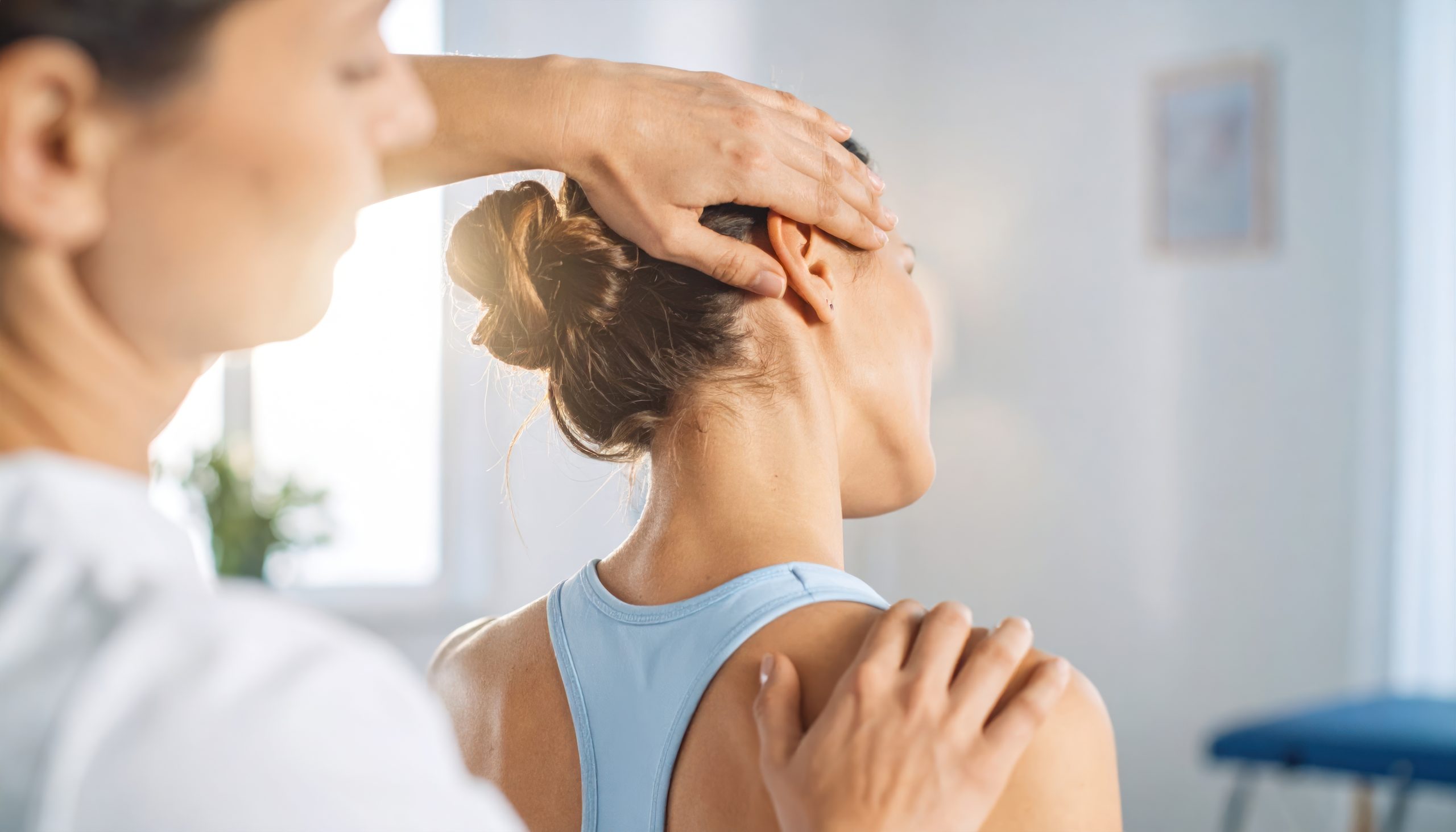 Manual osteopathic practitioner using gentle hands-on technique to support neck and shoulder movement